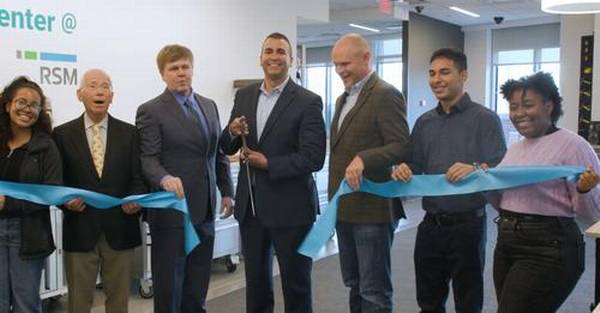 Picture of 7 individuals of various genders and ethnicities cutting a ribbon at a grand opening event.